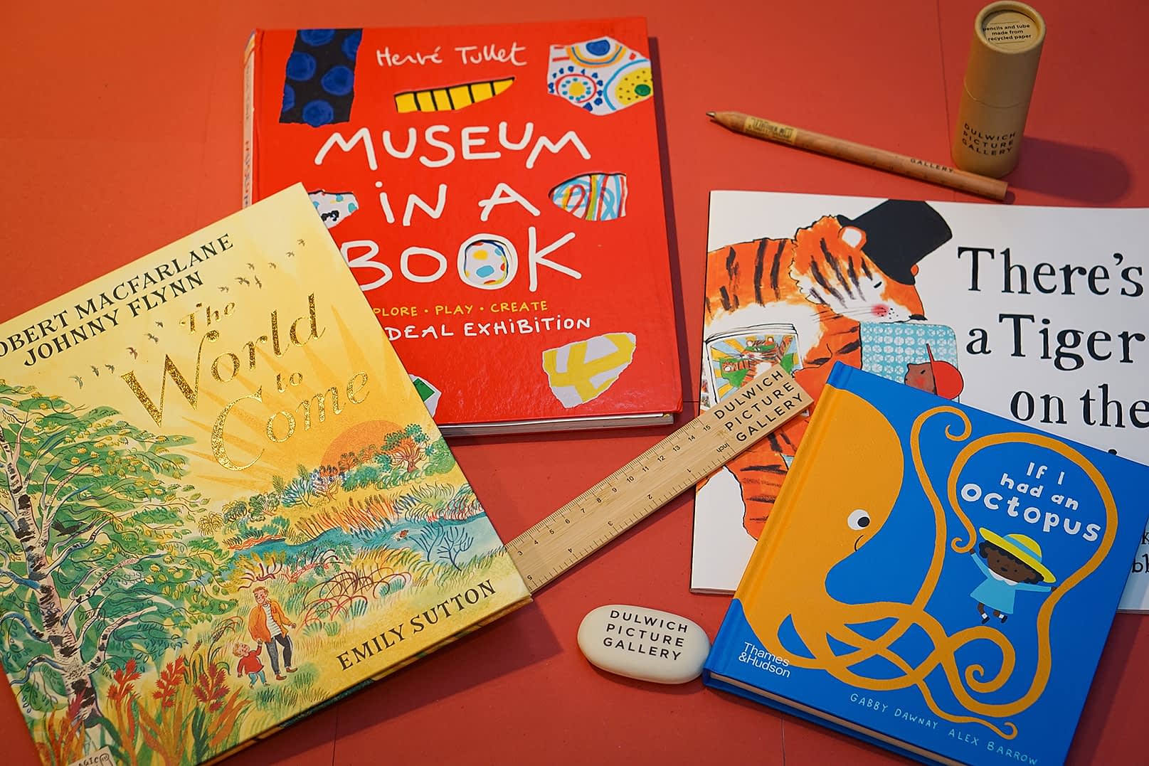 Photograph of 4 children's books on a red background with some stationary including a rules, rubber and some pencils